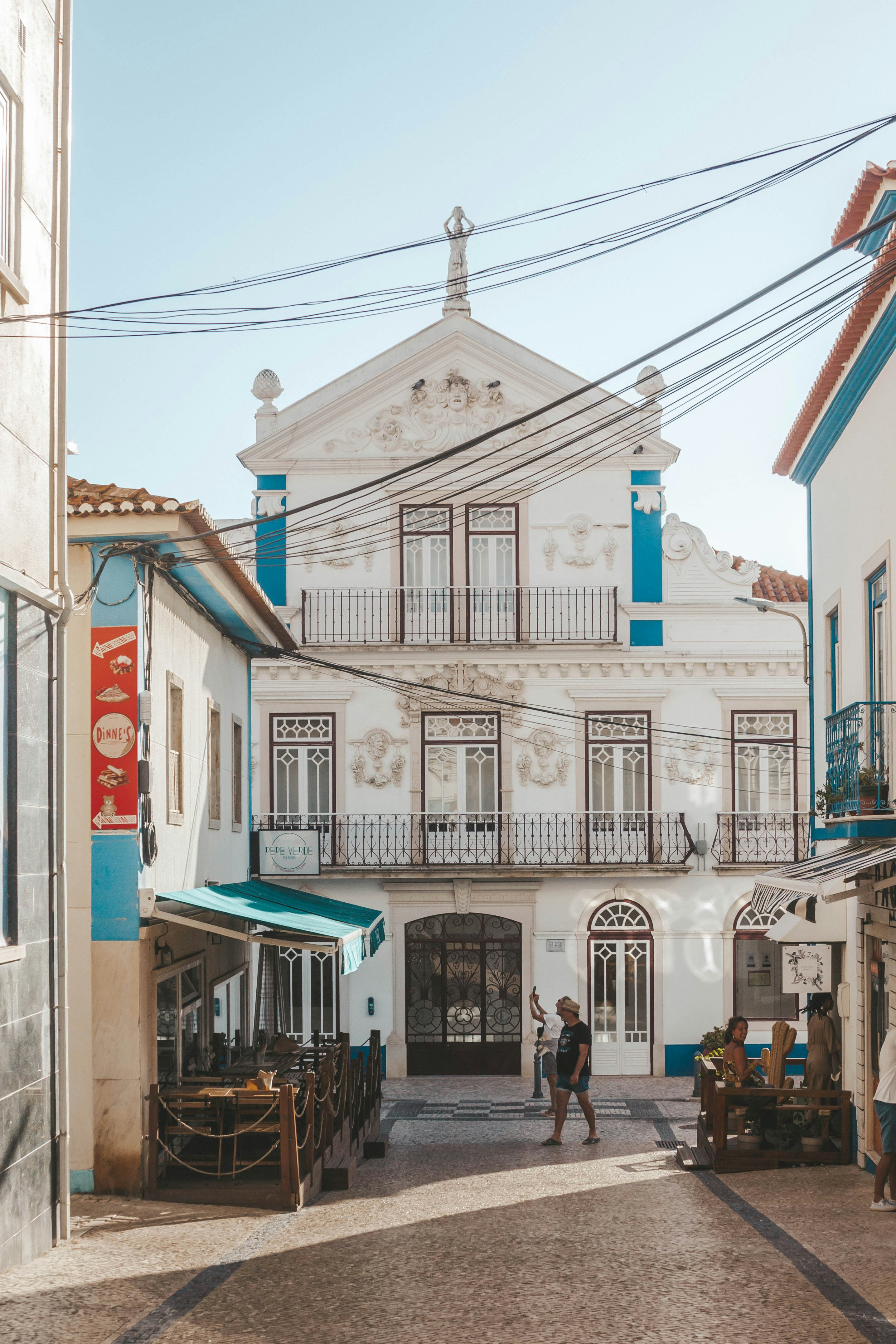 Whitewashed buildings with blue trim along a cobblestone street in Ericeira, Portugal